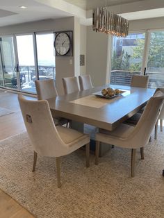 a dining room table with chairs and a clock on the wall