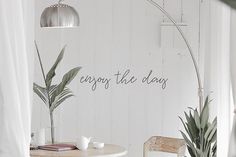 a table with two chairs and a potted plant next to it that says enjoy the day