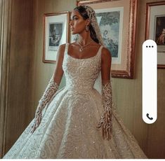 a woman in a wedding dress standing next to a wall with framed pictures on it