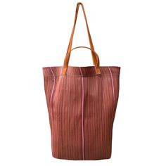 Each tote bag is meticulously stitched by artisans in Assam, India, under fair trade conditions, then finished with leather straps and detailing in Brooklyn, New York. Perfect for the market, beach, or everyday use, our tote bags not only support the livelihoods of our artisan partners but also help keep plastic out of landfills. perfect for a couple of bottles of wine and a baguette! H: 17" W: 16" Recycled Plastic and Leather. Handwoven Tote Bucket Bag For Everyday, Artisan Bucket Bag For Everyday Use In Summer, Everyday Handwoven Bucket Bag, Fair Trade Bucket Beach Bag For Daily Use, Red Shoulder Bag With Leather Handles For Market, Rectangular Beach Bag With Leather Handles For Market, Fair Trade Bucket Bag For Everyday Use, Market Tote Shoulder Bag With Leather Handles, Everyday Fair Trade Tote Bag