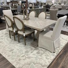 a dining room table with chairs and rugs on the floor in front of it