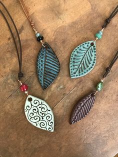 three necklaces with different designs on them sitting on top of a wooden table together