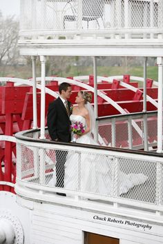 a bride and groom standing on the deck of a carnival ride at a fairground