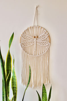 a white wall hanging next to a potted plant