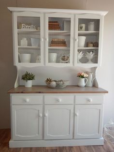 a white china cabinet filled with dishes and cups