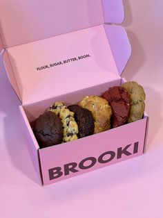 a pink box filled with cookies and muffins