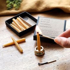 a person lighting a candle in a box with some matches on the table next to it