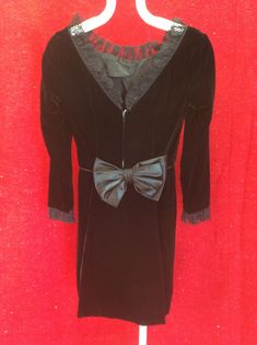 "This black velvet, oh-so fitted dress is in remarkable condition.  There is satin-piped 1.5\" lace at the cuffs, at the jewel neckline and extending all the way down the 9\" deep-vee back.  The back of the dress tells such a 60s story with a 10\" wide satin-lined apron topped with a 9\" satin bow.  If it was me, I'd be doing a lot of walking away and looking smolderinly over my shoulder.   Satin piping at waist.  7\" back zipper.  Unlined. Shoulder to shoulder 15\" Bust 34\" Waist 24\" Hips 38\" Length 14\" to waist; 35\" total Sleeves 16\" under arm; 22\" along the top." 60s Fashion Women, Full Skirts, 1940s Dresses, 80s Dress, The Jewel, 60s Dress, Jewel Neckline, Satin Gown, Satin Bow