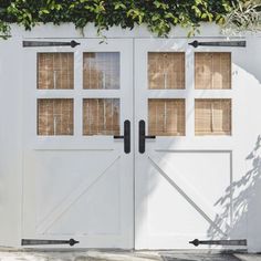 an image of two white doors that are open on the side of a building with ivy growing over it