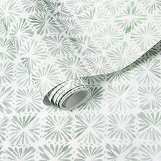 a white and green wallpaper with an intricate design on the wall, featuring leaves