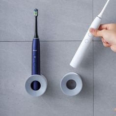 a person holding an electric toothbrush next to another one