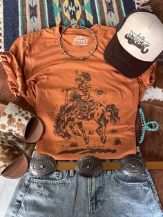 Channel your inner cowgirl with this bold and empowering tee. Featuring a striking rider graphic, it's perfect for those who embrace their wild side. Unisex fit  Made in the USA Womens Western T Shirts, Cowboy Graphic Tees, Cute Western Tops, Cowgirl Clothes, Western Apparel, Camping Aesthetic, Casual Bodysuit, Womens Jumpsuits, Dream Outfits