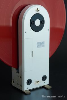 a white and red object sitting on top of a black table next to a red disc