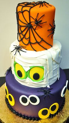 a three tiered halloween cake decorated with spider webs and eyeballs on top