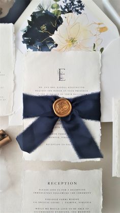 the wedding stationery is laid out on top of each other, with a ribbon tied around it