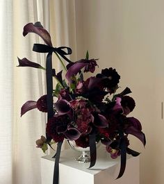 a vase filled with purple flowers on top of a white table