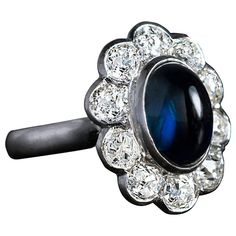 Mid century, circa 1950s A platinum cluster ring is bezel-set with a cabochon cut midnight blue sapphire surrounded by ten sparkling old mine cut diamonds, H-I-J color, VS1-SI1 clarity. Total diamond weight 2.43 Ct Sapphire 4.15 Ct Sapphire and diamond cluster measures 19 x 16 mm (3/4 x 5/8 in.) Ring size 6.75 (17 mm) sizable Morganite Engagement Ring Vintage, Bezel Set Engagement Ring, Pink Engagement Ring, Rose Gold Engagement Ring Vintage, Pink Sapphire Ring Engagement, Diamond Sapphire Engagement Ring, Sapphire Diamond Engagement, Contemporary Engagement Rings, Cute Engagement Rings