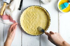 a person holding a fork near a pie on a white table with utensils