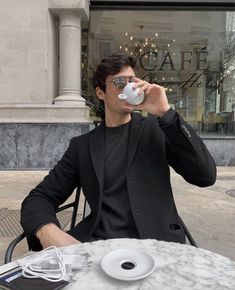 a man sitting at a table drinking from a cup