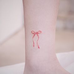 a small red bow tattoo on the ankle