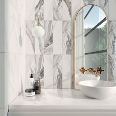 a white sink sitting under a bathroom mirror next to a wall mounted faucet