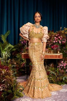 Introducing our "Golden Glamour Lehenga" - a stunning mermaid lehenga embellished with golden metals, sequins, and dangling chains. The tube blouse features intricate jhaali work with elegant latkans, paired with a hand draped jacket for an extravagant touch. Experience the allure of opulence and grace in this mesmerizing ensemble, designed to make you shine on your special day. Colour: Gold Fabric: Tulle Technique: Hand Embroidery No of set: 3 Delivery Time: 8-10 weeks Washcare: How to Store yo Mermaid Indian Dress, Mermaid Lehenga Indian Fashion, Heeramandi Costumes, Golden Lengha, Heeramandi Outfits, Lehenga Shoot, Contemporary Lehenga, Mermaid Lehenga, Tube Blouse