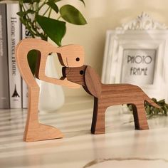 a wooden sculpture of a dog with its head in the other's mouth, standing on a table