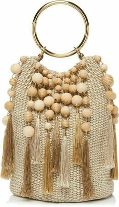 a handbag with wooden beads and tassels on the handles, hanging from a gold ring