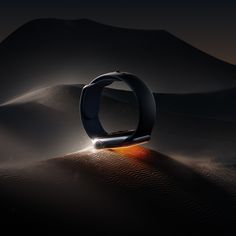 an image of a ring in the middle of sand dunes at night with light coming from it