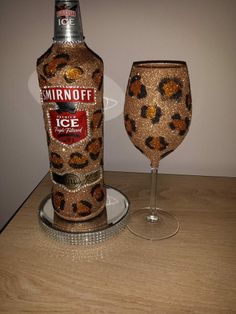 a wine glass and bottle sitting on a table next to each other with a leopard print design