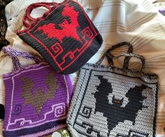 three crocheted purses sitting on top of a white bed next to each other