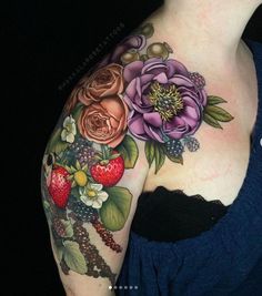 a woman's shoulder with flowers and berries on it