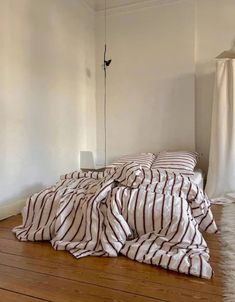 a bed sitting on top of a wooden floor next to a white wall and window