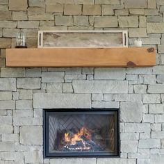 a stone fireplace with a wood mantle and fire