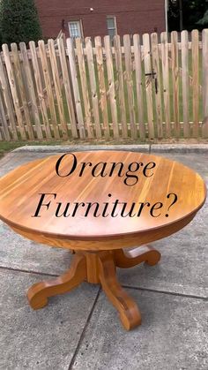 a wooden table with the words orange furniture written on it in front of a fence