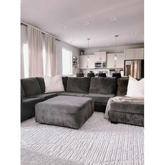 a living room with gray couches and white rugs on the floor in front of windows