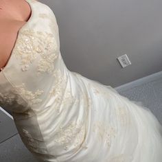 the back of a wedding dress is being held up by a woman's hand