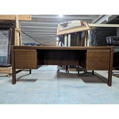 a wooden desk with two drawers and an umbrella over it's head in a warehouse