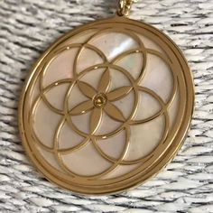 "Seed of Life in 24 carat gold on 925 silver, mother of pearl backdrop and Peridot crystal. The symbol commonly referred to as the Seed of Life is made up of seven circles; one in the center, and six others placed around it according to ancient spiritual traditions. It's tought that the seven interlocking circe are compared to the seven days of creation, with the different circles being ascribed to different points in the universe's making. The flore blooming in the middle is considered the Cons Spiritual Round Mother Of Pearl Jewelry, Spiritual Gold Necklace With Mother Of Pearl, Pearl Backdrop, Pearl Background, Peridot Crystal, Seed Of Life, Spiritual Symbols, Yoga And Meditation, Star Pictures