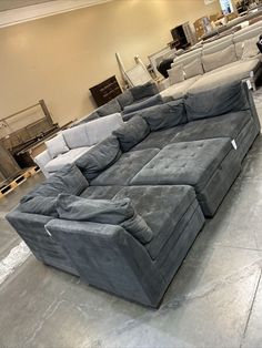 a large gray couch sitting on top of a floor next to a pile of chairs