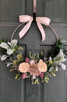 a wreath with flowers and greenery hangs on the front door