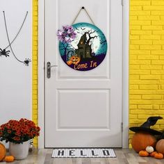 a white door with a welcome sign on it and pumpkins in front of it