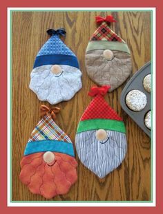 four oven mitts decorated to look like santa claus and other christmas decorations on a table