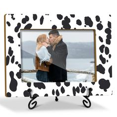 a black and white cow print frame with a couple kissing