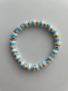 a blue and white beaded bracelet with gold accents on a white surface, top view