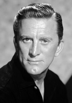 a black and white photo of a man with short hair wearing a shirt looking at the camera