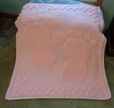 a crocheted blanket with baby booties on it