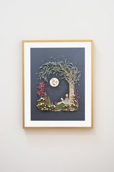 a framed photo of a fairy tale scene on a white wall with a gold frame