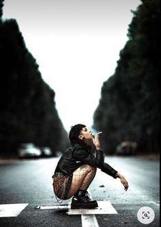 a woman kneeling down on the side of a road drinking from a water bottle while wearing fishnet stockings