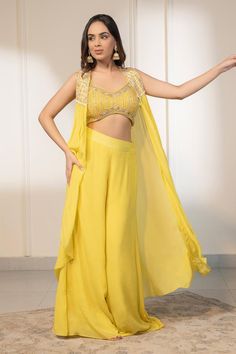 Yellow cape with placement sequin embellishments. Paired with an inner padded blouse with all over crystals, sequins embellishments. Comes along with a flared pant.
Components: 3
Pattern: Embellished
Type Of Work: Crystals, Cutdana
Neckline: V Neck
Sleeve Type: Sleeveless
Fabric: Blouse: Net, Pant and Cape: Crepe
Color: Yellow
Other Details: 
Length:
Pant: 42 inches
Blouse: 14 inches
Padded blouse
Occasion: Sangeet - Aza Fashions Glamorous Embellished Georgette Sets, Glamorous Embellished Floor-length Palazzo Set, Glamorous Resham Embroidery Sets, Glamorous Embellished Palazzo Set For Reception, Embellished Georgette Palazzo Set For Evening, Glamorous Embellished Palazzo Set For Party, Festive Embellished Evening Pant Set, Festive Evening Embellished Pant Set, Designer Embellished Georgette Pant Set